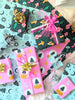 Photo shows a pile of beautifully wrapped holiday gifts in magical, bohemian inspired hand illustrated wrapping paper. Gifts are wrapped with ribbons and bows, and there is a vintage glass tree in the background.