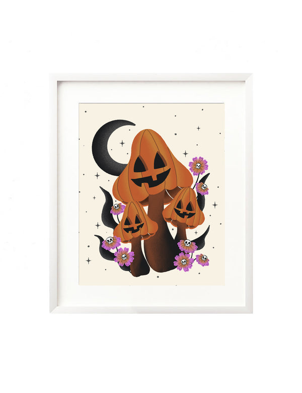 A framed art print - the illustration is of whimsical mushrooms drawn with jack o lantern faces, and colored orange for Halloween. It is surrounded by vibrant florals that have skull heads in the center and a crescent moon and twinkling stars make up the background. 
