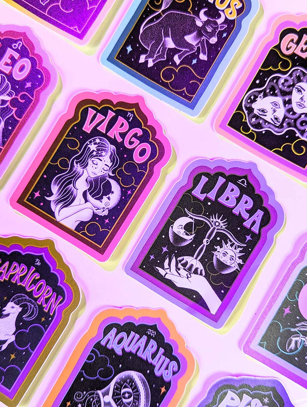 A collection of zodiac stickers sits on a white background with purple aura glow lights. There are illustrated stickers of each astrological sign, with a retro hand lettering spelling out the name of each sign. Stickers for Aries, Taurus, Cancer, Gemini, Leo, Virgo, Libra, Scorpio, Sagittarius, Capricorn, Aquarius, and Pisces. Water sign, Fire Sign, Earth Sign, Air Sign. Surrounded by clear quartz crystals. Witchy. Witch. Boho. Bohemian. Astrology Girlie. Yoga. Yogi.