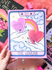 Three art prints are shown with scattered star confetti, glitter nail polish, and a pink background. One print is held up, it features who hands, each holding a candy heart with hand lettering phrases "You're Cute" and "Be Mile" a rainbow connects the hearts and in the background are whimsical clouds, stars, and magical twinkles. A perfect gift for Valentine's Day, or just because for your lover, or any magical witchy woman!