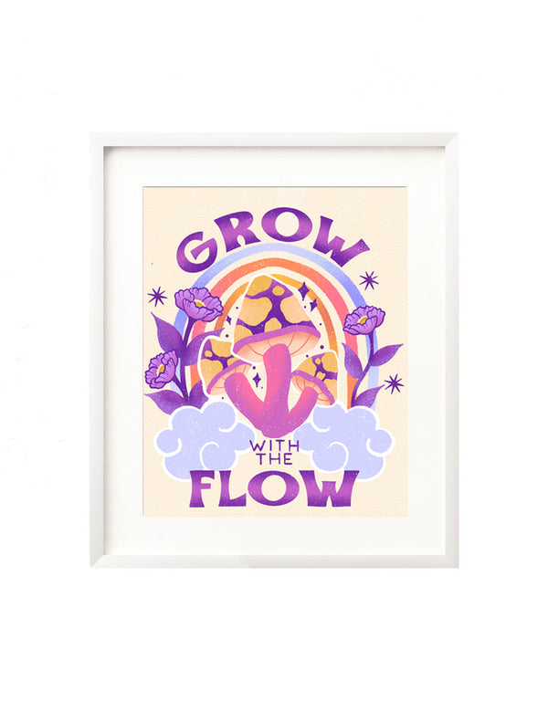 A framed art print - the illustration is of a bright whimsical grouping of mushrooms, surrounded by fluffy clouds, vibrant florals and twinkling stars. There is a colorful rainbow emerging in the background and hand lettering spells out "Grow with the Flow" in a funky, retro inspired style all in a vibrant color palette of pink, purple, yellow, and periwinkle.