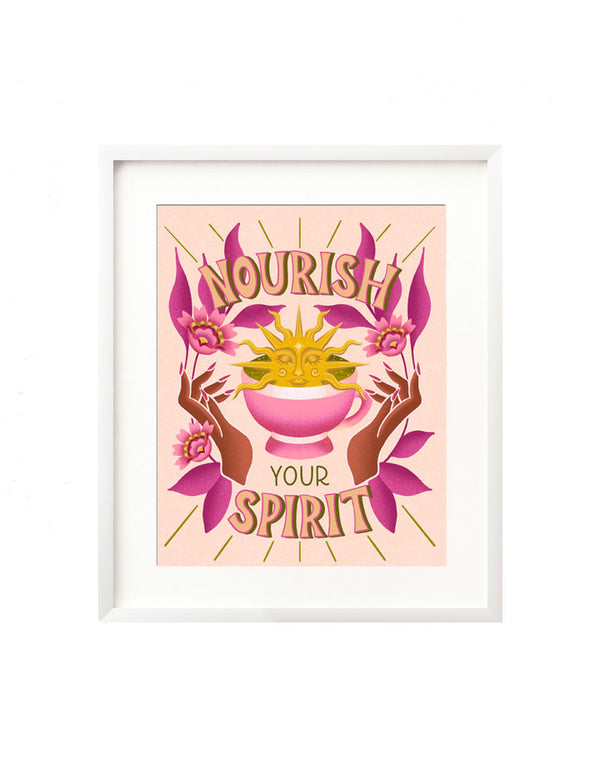 A framed art print - the illustration is of a golden sun rising from a cozy pink cup of matcha tea. There are hands on either side summoning it, and it is framed in by vibrant folk inspired florals and leaves. Hand lettered above and below is "Nourish your spirit" in a funky, retro inspired style. 