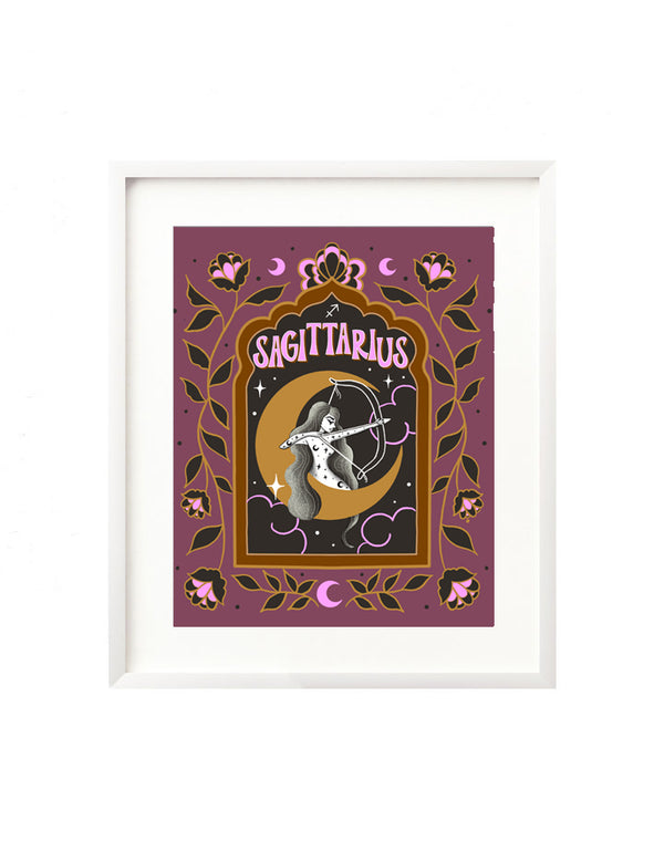 A framed art print - the illustration is a depiction of the Sagittarius zodiac sign. The celestial archer is illustrated floating in a starry night sky, surrounded by whimsical clouds and framed in by folk art flowers. Sagittarius is hand lettered at the top in a bold, groovy, retro inspired style.