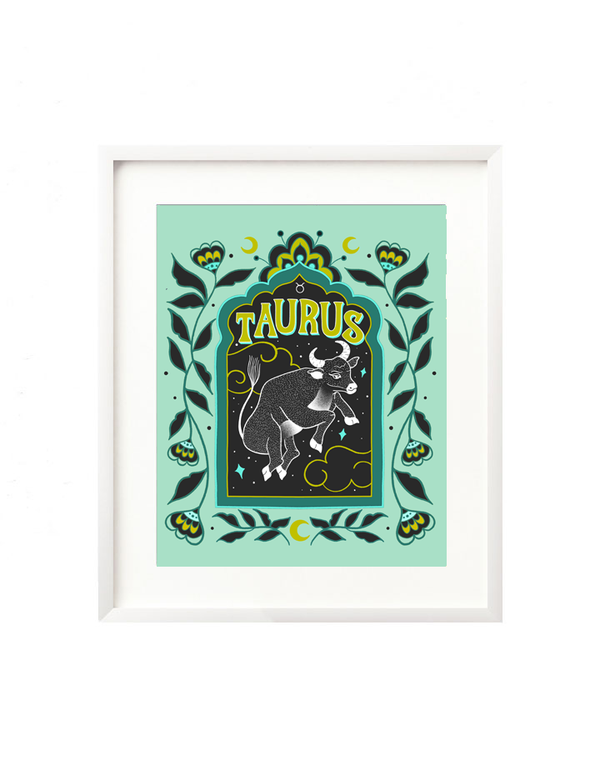 A framed art print - the illustration is a depiction of the Taurus zodiac sign. The celestial bull is illustrated floating in a starry night sky, surrounded by whimsical clouds and framed in by folk art flowers. Taurus is hand lettered at the top in a bold, groovy, retro inspired style.