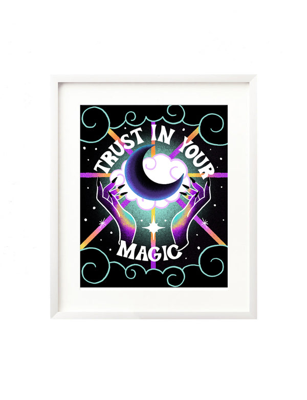 A framed art print - the illustration features rainbow colored hands in shades of blue, yellow, purple, and black summoning a crescent moon atop fluffy clouds. There are swirling clouds, rainbow colored light beams, and twinkling stars surrounding the art. Hand lettered is "Trust in your magic" in a retro style.