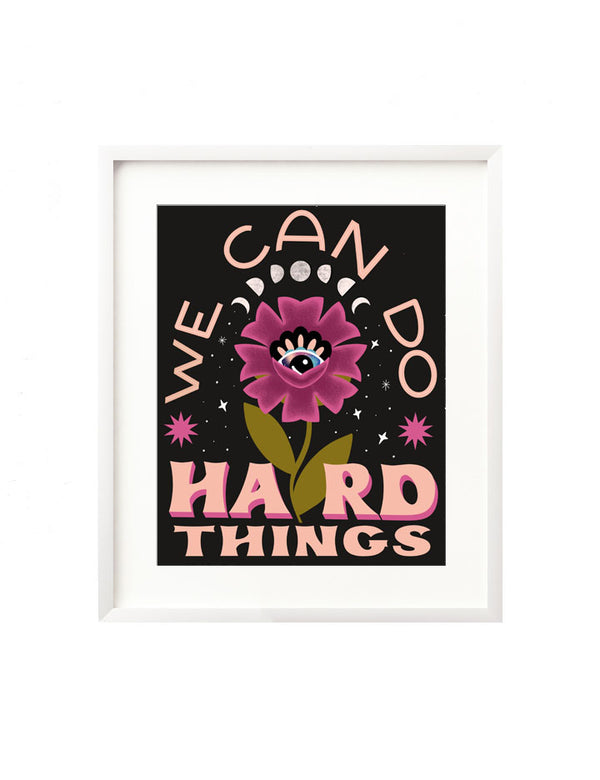 A framed art print - the illustration features a blooming floral with an intuitive eye at the heart of it. There are moon phases above and twinkling stars surrounding it and the hand lettered message "We can do hard things" frames it in, inspire by Glennon Doyle's book "Untamed".
