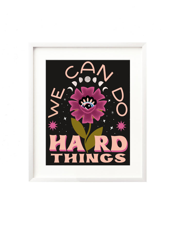 A framed art print - the illustration features a blooming floral with an intuitive eye at the heart of it. There are moon phases above and twinkling stars surrounding it and the hand lettered message "We can do hard things" frames it in, inspire by Glennon Doyle's book "Untamed".